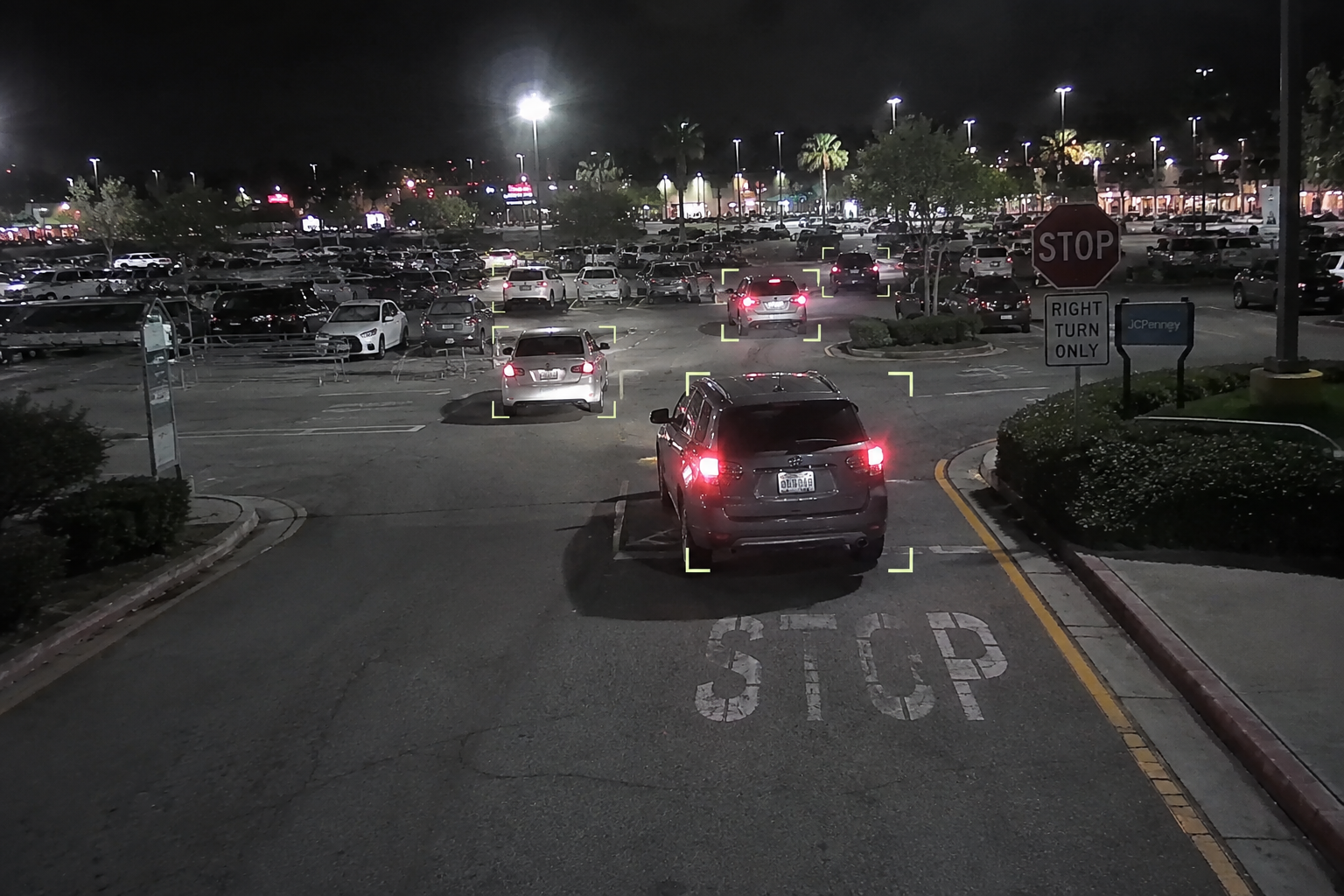 Night parking lot camera view with vehicles detected and bracketed